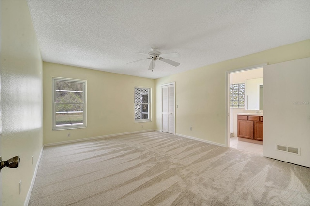 spare room with light carpet, ceiling fan, and a textured ceiling