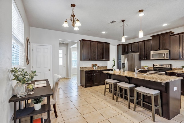 kitchen featuring appliances with stainless steel finishes, dark brown cabinets, and pendant lighting