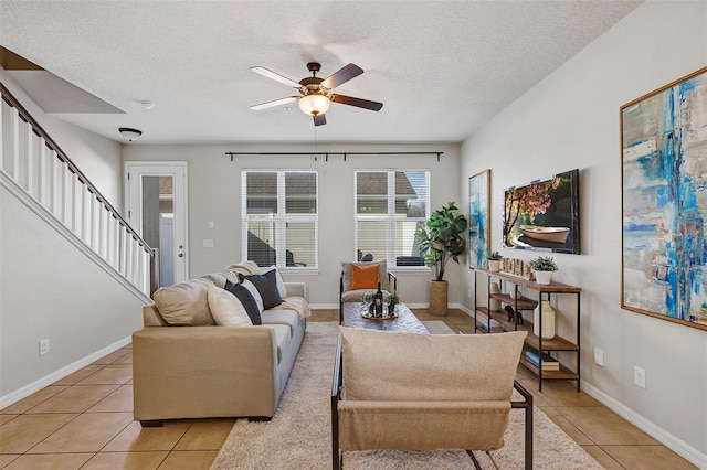 living room featuring ceiling fan, light tile patterned floors, and a textured ceiling