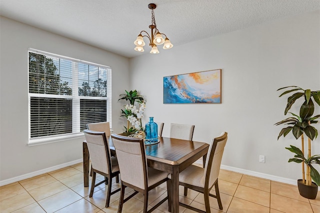 tiled dining area featuring an inviting chandelier and a textured ceiling