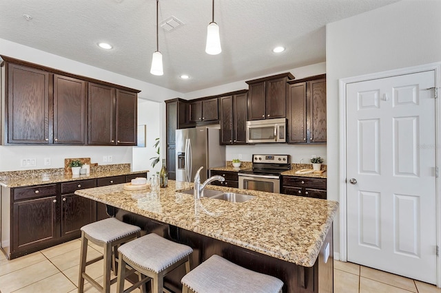 kitchen with appliances with stainless steel finishes, a breakfast bar, sink, and a center island with sink