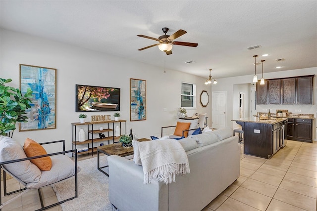 living room with light tile patterned floors, a textured ceiling, sink, and ceiling fan