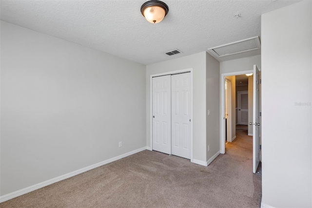 unfurnished bedroom featuring light carpet, a closet, and a textured ceiling