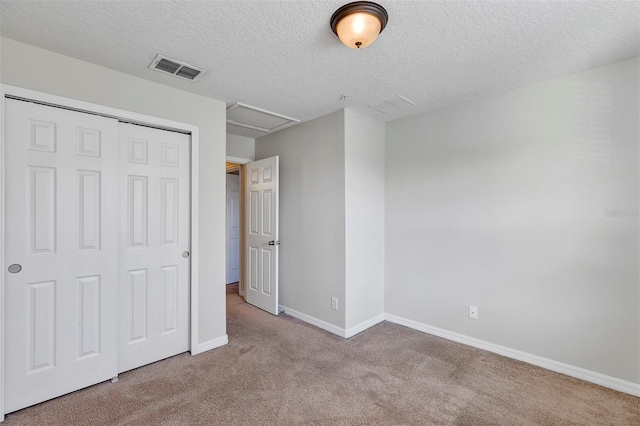 unfurnished bedroom with light colored carpet, a textured ceiling, and a closet