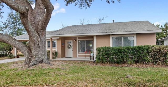 ranch-style home with a shingled roof and a front yard