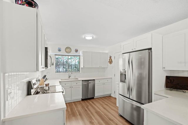 kitchen featuring appliances with stainless steel finishes, light countertops, a sink, and tasteful backsplash