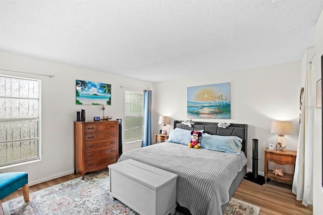 bedroom with light hardwood / wood-style floors and a textured ceiling