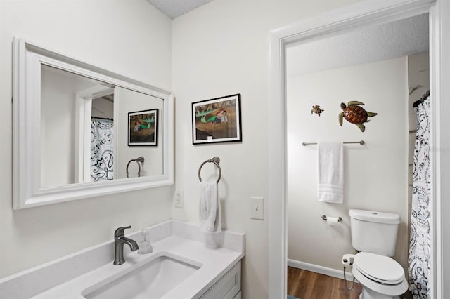 bathroom featuring vanity, hardwood / wood-style flooring, a textured ceiling, and toilet