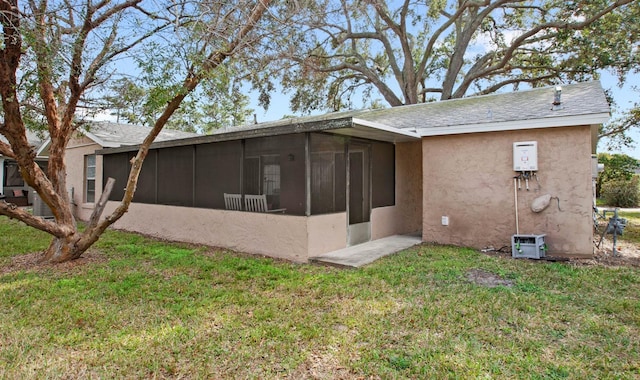 rear view of house with a sunroom, a lawn, and stucco siding