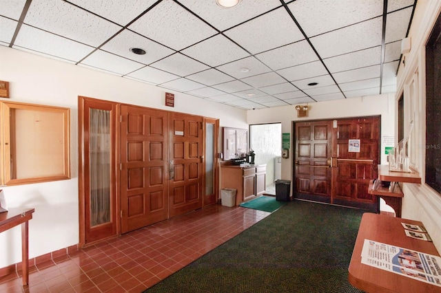 entryway featuring dark tile patterned floors and a drop ceiling