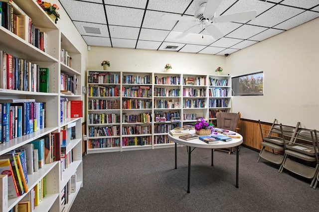 interior space with ceiling fan, a paneled ceiling, and carpet