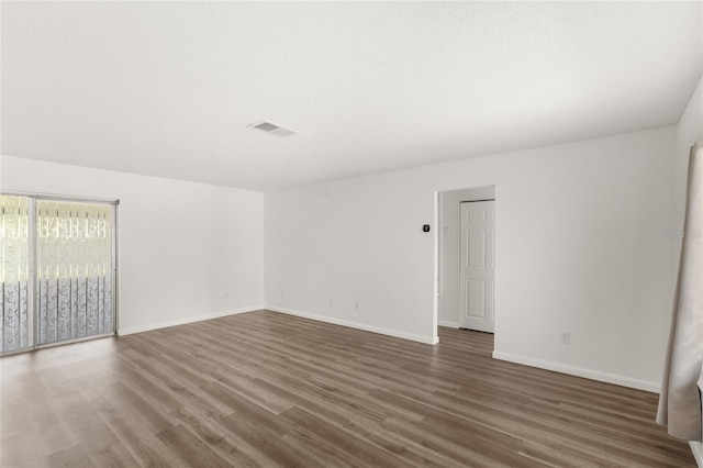 spare room with baseboards, a textured ceiling, visible vents, and wood finished floors