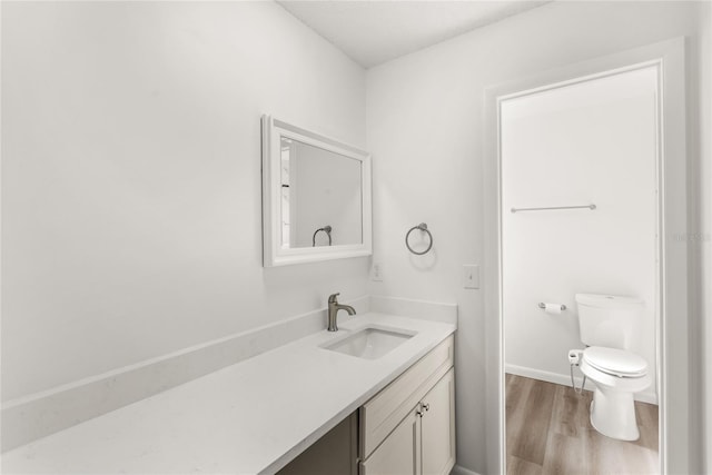 bathroom featuring toilet, wood finished floors, vanity, and baseboards