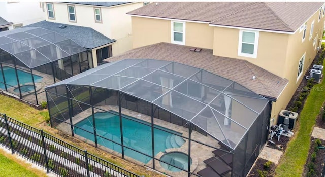 view of pool featuring a patio, glass enclosure, and an in ground hot tub