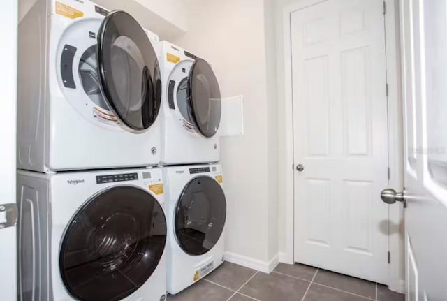 clothes washing area with stacked washer / drying machine and dark tile patterned floors