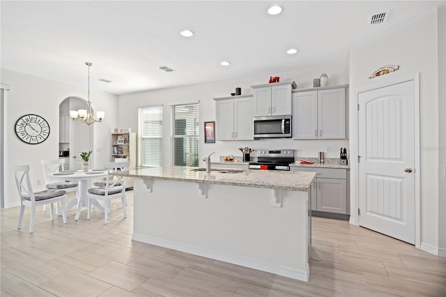 kitchen with sink, a breakfast bar area, gray cabinetry, a kitchen island with sink, and stainless steel appliances