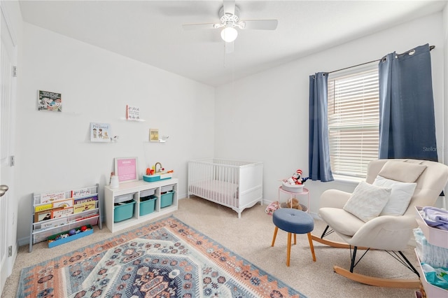 carpeted bedroom with a nursery area and ceiling fan