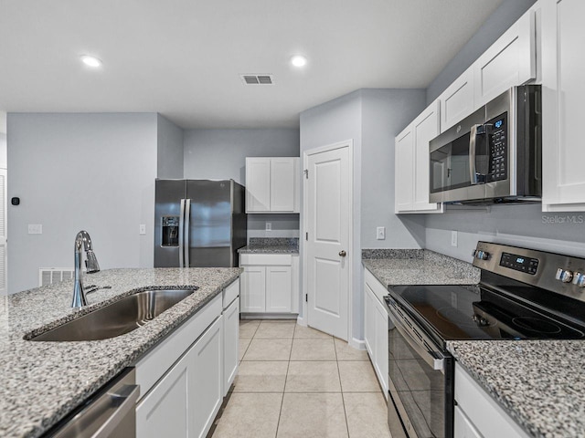 kitchen with sink, light tile patterned floors, appliances with stainless steel finishes, light stone countertops, and white cabinets