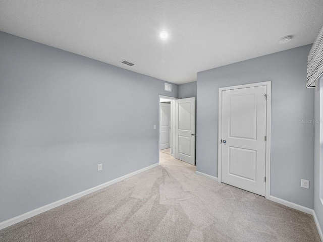 unfurnished bedroom featuring light carpet and a textured ceiling