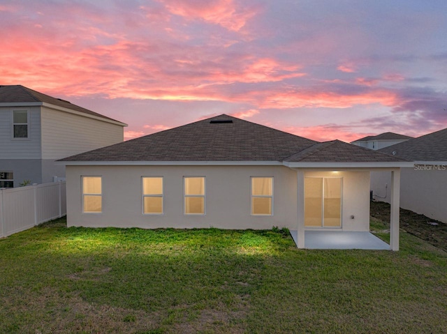 back house at dusk with a yard and a patio area