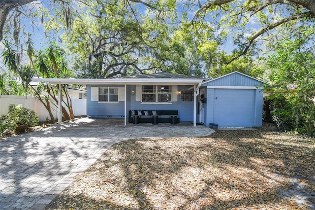 ranch-style house with a carport, fence, decorative driveway, and an outbuilding