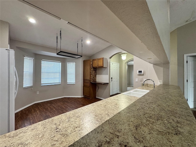 kitchen with vaulted ceiling, white fridge, sink, and dark hardwood / wood-style floors