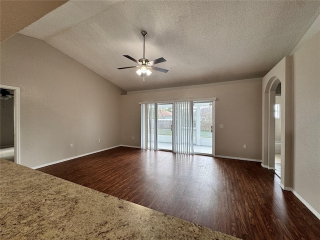 unfurnished room with vaulted ceiling, dark hardwood / wood-style floors, a textured ceiling, and ceiling fan