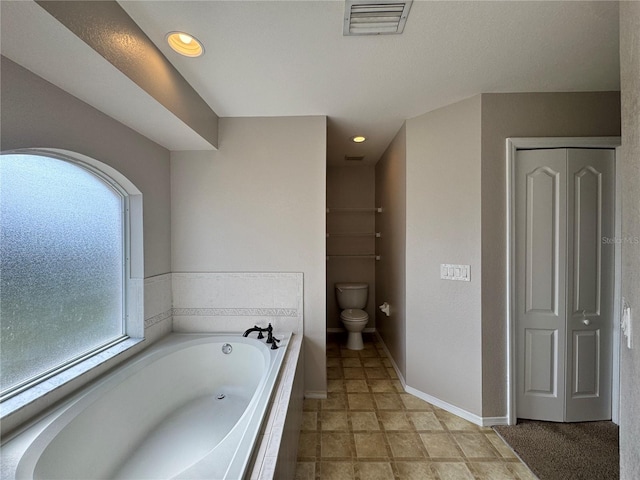 bathroom with toilet and tiled tub