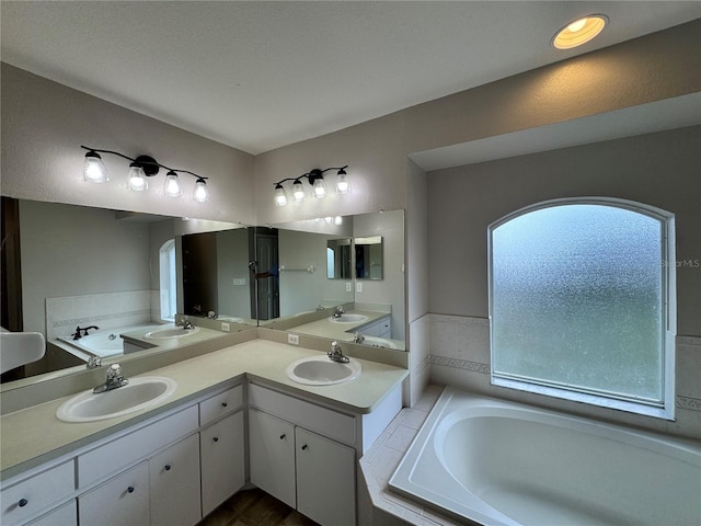 bathroom featuring tiled tub and vanity