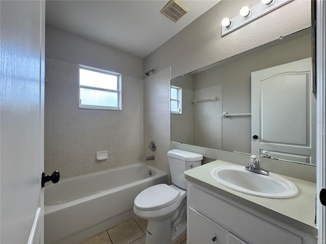 full bathroom featuring tile patterned flooring, vanity, tiled shower / bath combo, and toilet