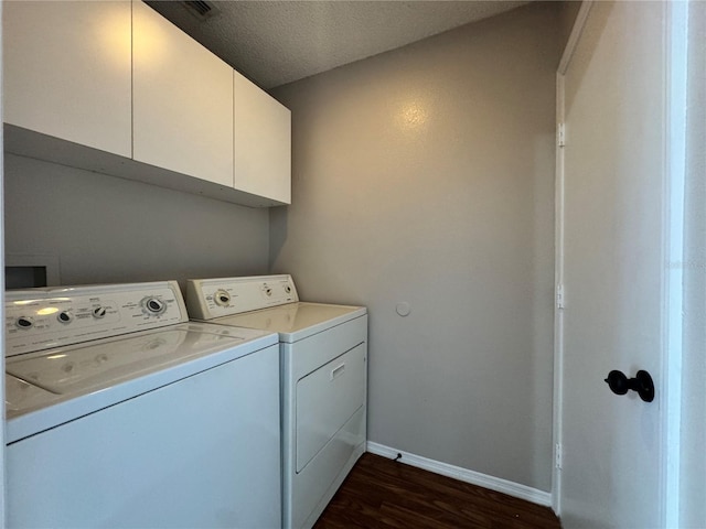 washroom featuring dark hardwood / wood-style flooring, washer and clothes dryer, cabinets, and a textured ceiling