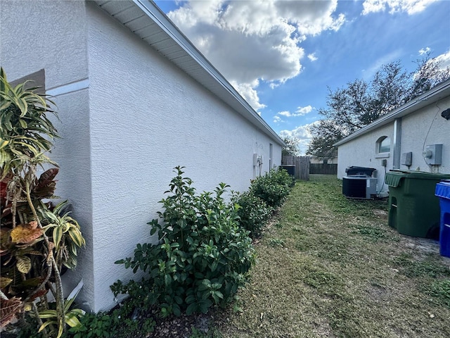 view of side of home with cooling unit and a lawn