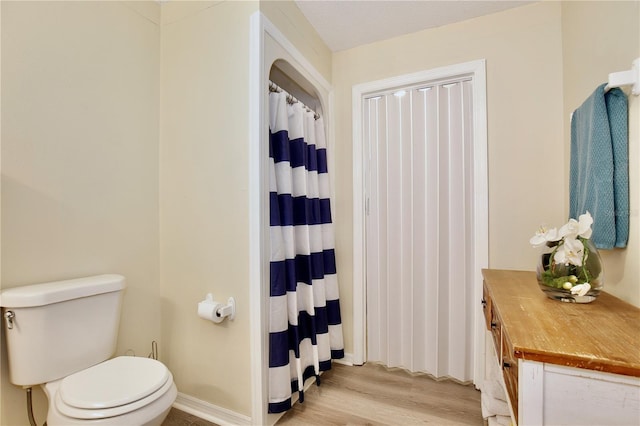 bathroom with wood finished floors, toilet, and baseboards