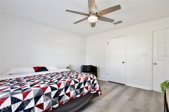 bedroom featuring baseboards, light wood-type flooring, visible vents, and a ceiling fan