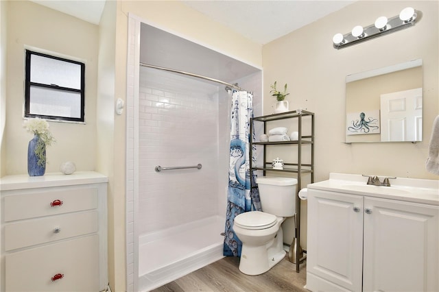 bathroom featuring vanity, tiled shower, wood finished floors, and toilet