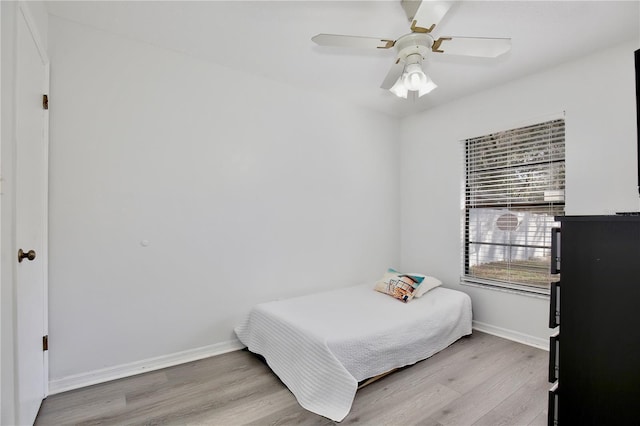 bedroom featuring ceiling fan, light wood-style flooring, and baseboards