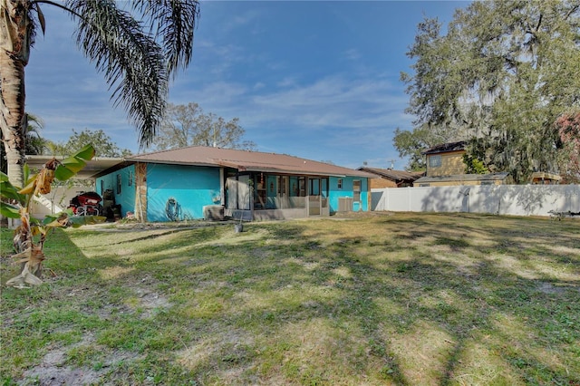 back of property with fence, metal roof, and a lawn