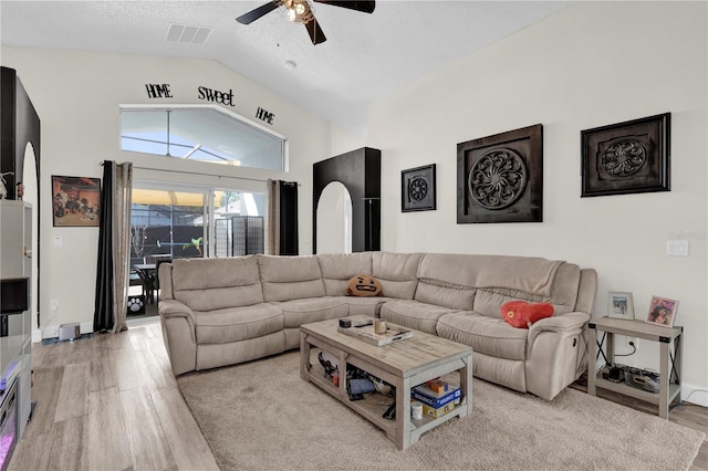 living room featuring ceiling fan, lofted ceiling, light hardwood / wood-style floors, and a textured ceiling