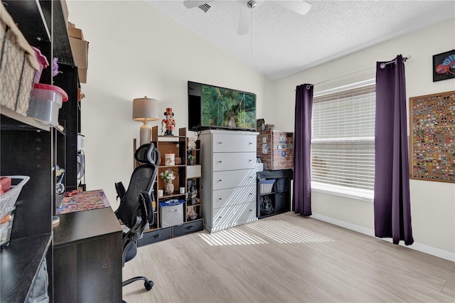 office space with ceiling fan, lofted ceiling, a textured ceiling, and light wood-type flooring