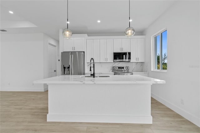 kitchen with hanging light fixtures, appliances with stainless steel finishes, and a center island with sink