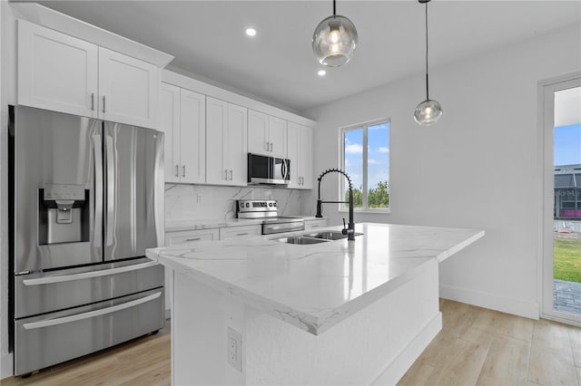 kitchen with pendant lighting, sink, appliances with stainless steel finishes, an island with sink, and white cabinets