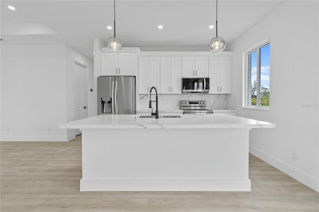 kitchen featuring sink, decorative light fixtures, an island with sink, and appliances with stainless steel finishes