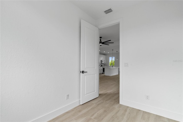 empty room with ceiling fan and light wood-type flooring