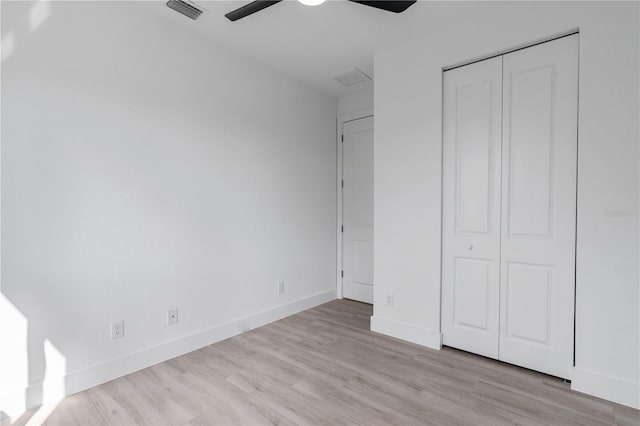 unfurnished bedroom with ceiling fan, light wood-type flooring, and a closet