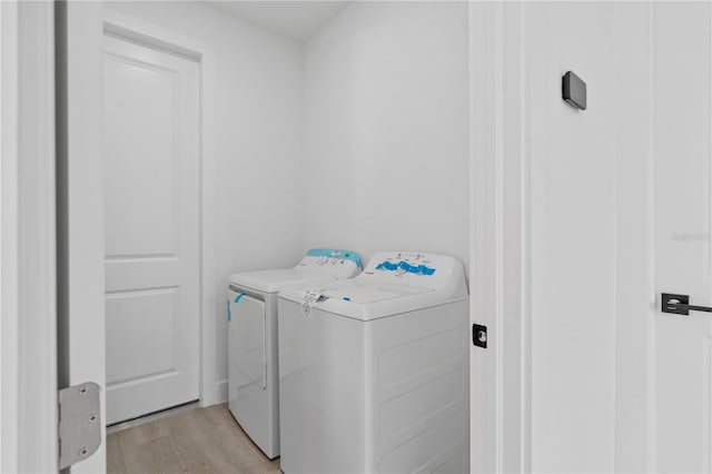 clothes washing area featuring separate washer and dryer and light wood-type flooring