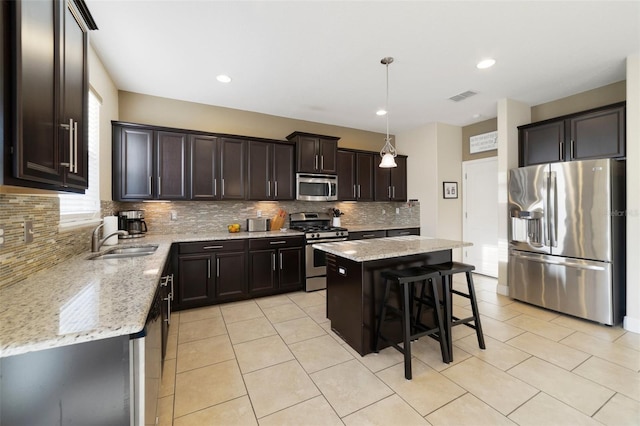 kitchen featuring sink, dark brown cabinets, stainless steel appliances, a center island, and decorative light fixtures