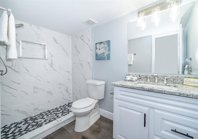 bathroom with vanity, wood-type flooring, toilet, and a tile shower