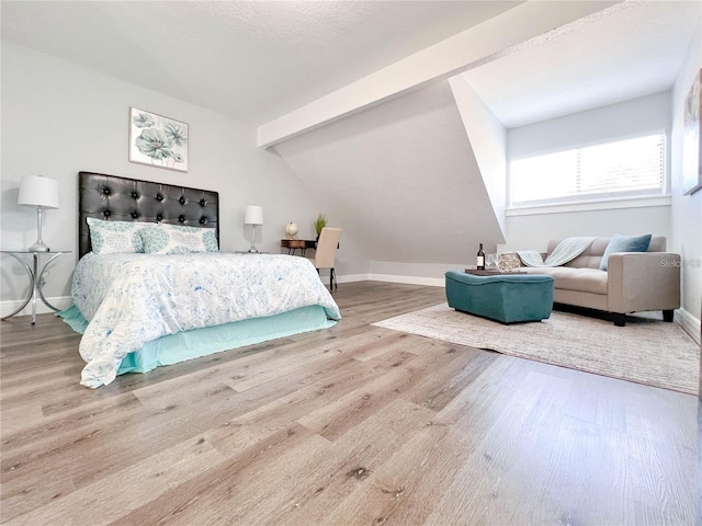 bedroom featuring hardwood / wood-style floors and vaulted ceiling with beams