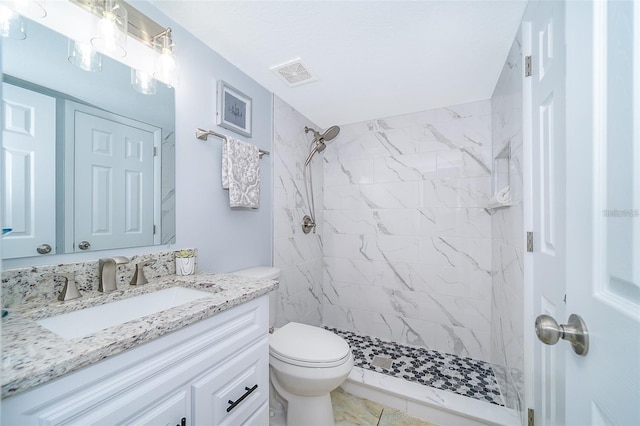 bathroom featuring vanity, a tile shower, and toilet