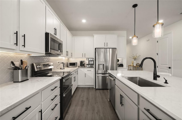 kitchen with white cabinetry, appliances with stainless steel finishes, sink, and light stone counters